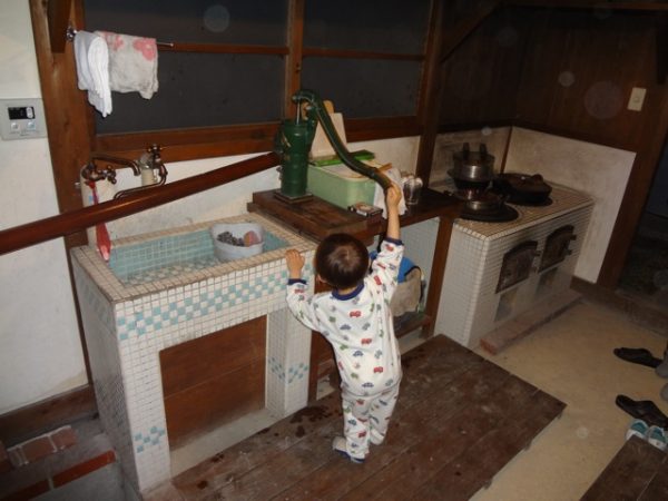 Criança de pijamas puxando água na cozinha
