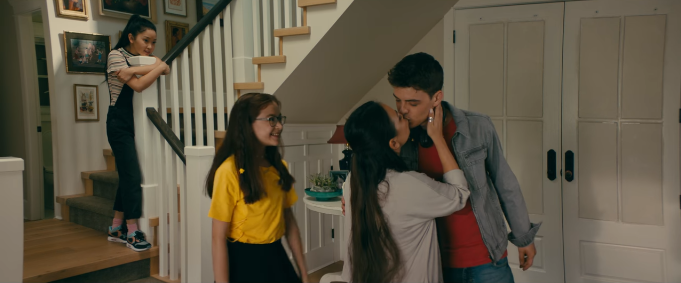 Lara Jean vendo da escada sua irmã beijar seu crush e vizinho, Josh Sanderson
