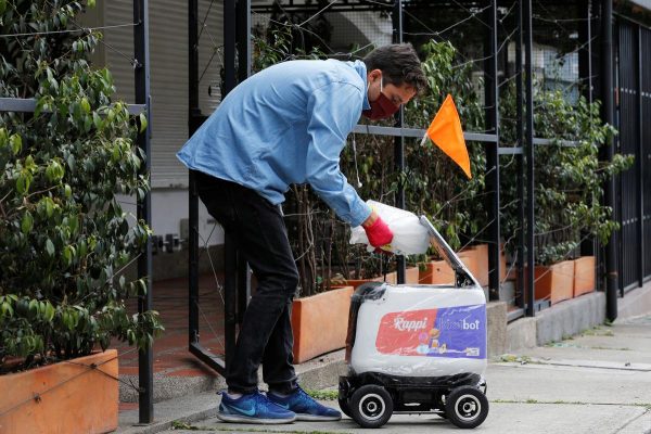 Um homem usando uma máscara facial coloca um pacote dentro de um robô de entrega da empresa colombiana Rappi, em meio ao surto de doença por coronavírus (Covid-19) em Medellín, Colômbia